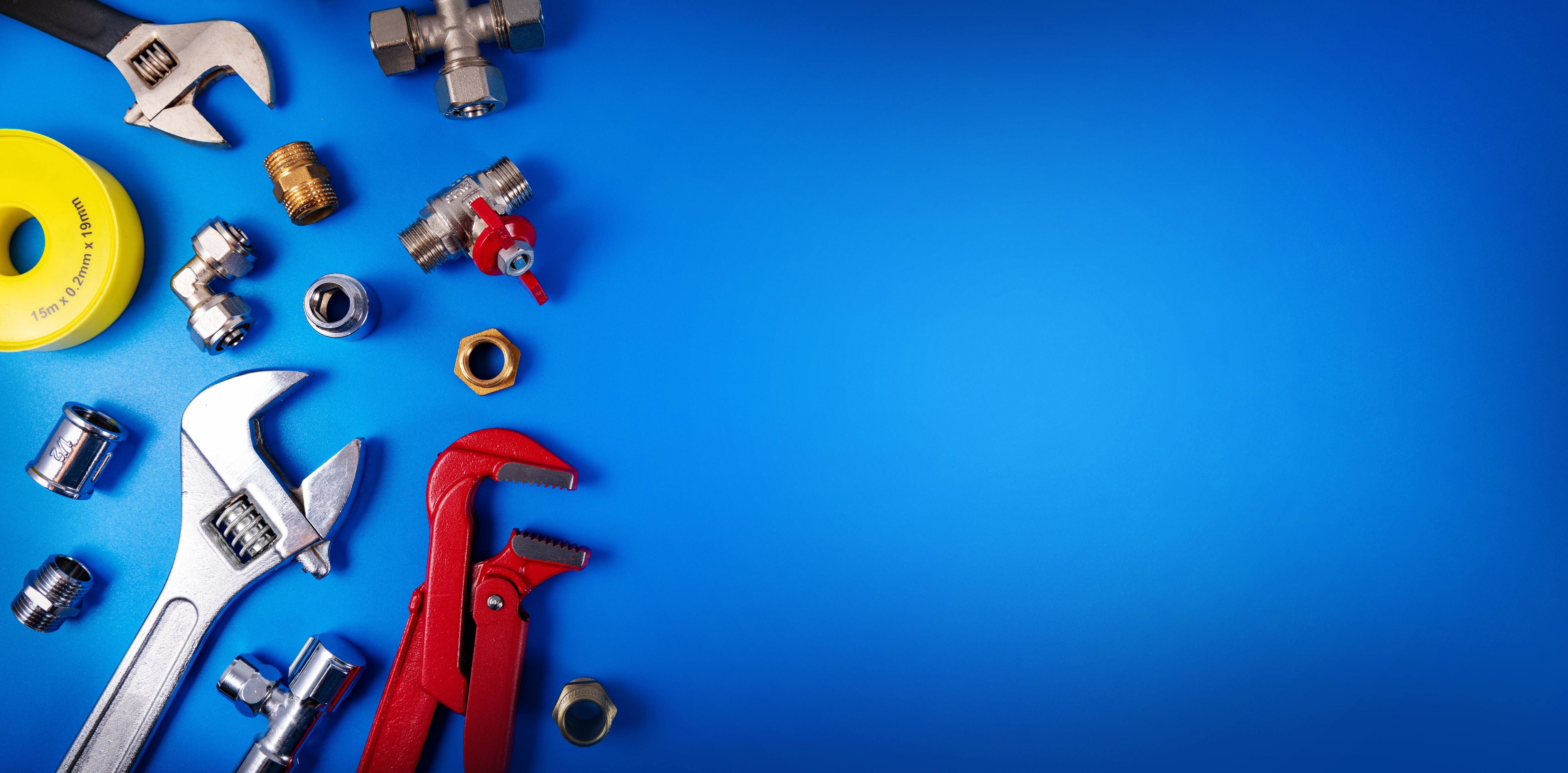 plumbing tools and fittings on blue background with copy space